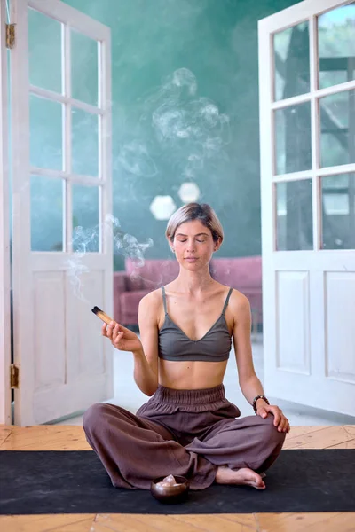 Un bastone aromatico indiano brucia, una femmina calma medita a casa, si rilassa — Foto Stock