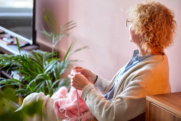 70s vieille femme assise sur la chaise, tricot grand-mère à la maison, réduit le stress — Photo