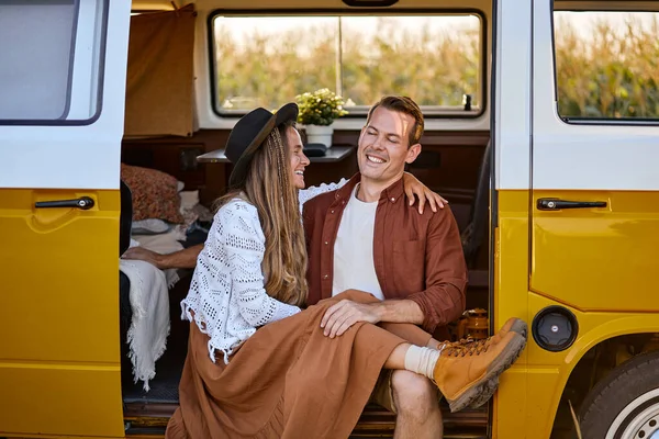 Красива весела пара сидить всередині кампервана, дивлячись за межами фургона — стокове фото