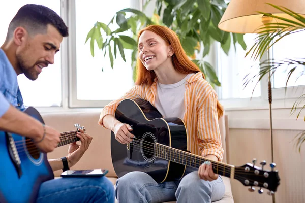 Стильный мужчина и красивая женщина, играющие песни на гитаре — стоковое фото