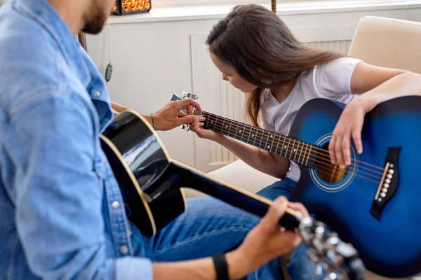 Семейное время. Отец и дочь вместе дома. Усердные маленькая девочка и отец играют на гитаре — стоковое фото