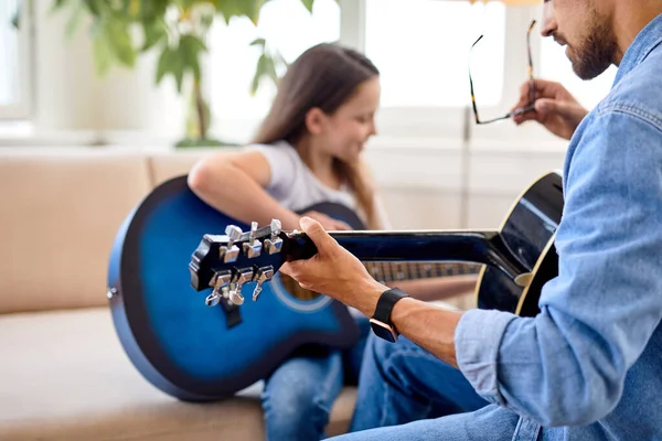 Обрезанный мужчина и симпатичная девочка, играющая песню на гитарном инструменте, крупным планом руки — стоковое фото