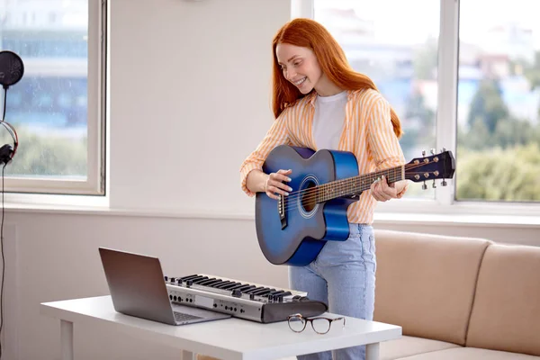 Guapa caucásica bonita mujer aprendiendo a tocar la guitarra en línea con el profesor —  Fotos de Stock