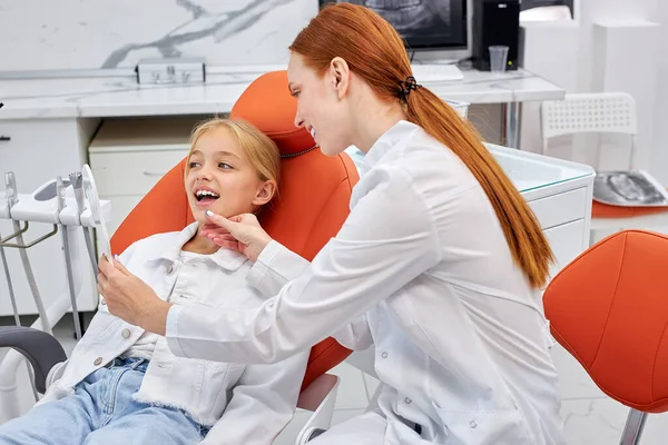 Sidovy på kvinnlig tandläkare i uniform fungerar med barn patient i tandläkarmottagningen — Stockfoto