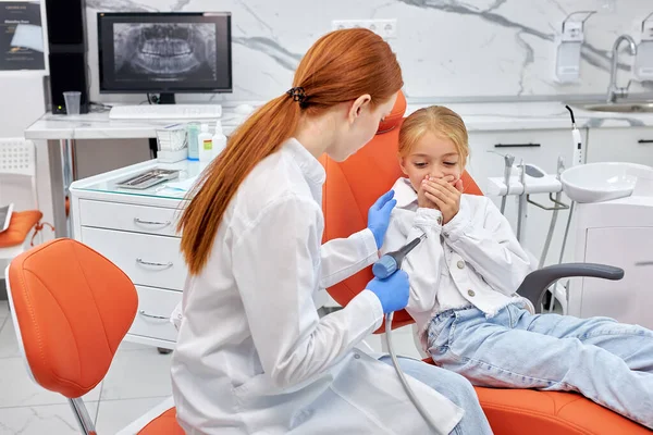 Rödhårig tandläkare kommer att utföra tandfyllning förfarande till skrämda barn — Stockfoto