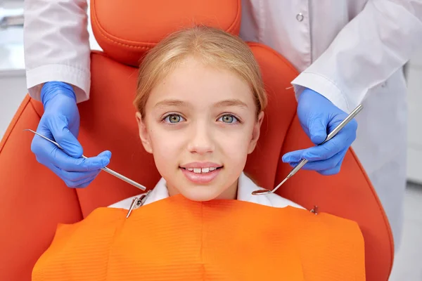 Ένα κοριτσάκι ήρθε να δει τον οδοντίατρο. Το παιδί κάθεται στην οδοντιατρική καρέκλα. Ο οδοντίατρος έσκυψε πάνω της — Φωτογραφία Αρχείου