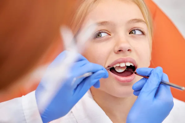 Приваблива біла дитина, що відвідує стоматолога, лікар робить огляд зубів — стокове фото