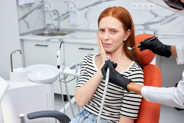 Καλλιεργημένος οδοντίατρος που εκτελεί οδοντιατρική διαδικασία πλήρωσης σε φοβισμένη γυναίκα στην οδοντιατρική κλινική. — Φωτογραφία Αρχείου