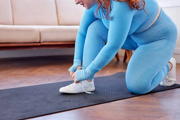 在家里锻炼的时候，在健身垫上割破了的胖女人的鞋带. — 图库照片