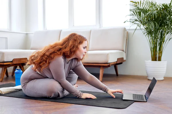 Fitness, online kişisel antrenör, evde eğitim, teknoloji ve diyet. Aşırı kilolu bir kadın yoga egzersizleri yapıyor. — Stok fotoğraf