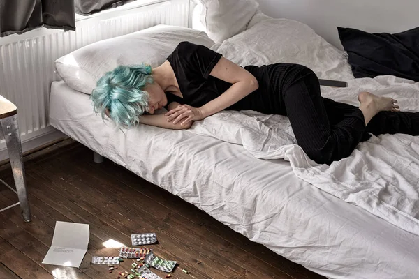 Tabletten auf dem Boden verteilt, weinende Frau liegt nach Tablettenüberdosis zu Hause im Bett — Stockfoto