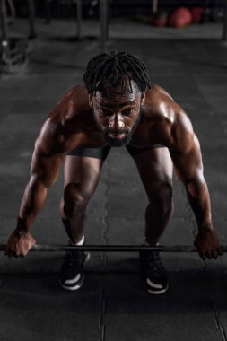 Kendine güvenen Afro-Amerikan adam spor salonunda halterli çömelme antrenmanı yapıyor..