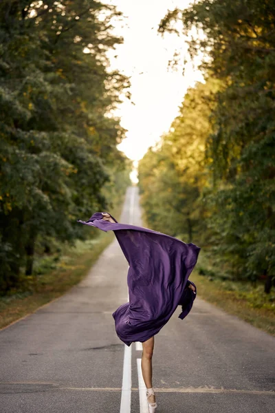 Femme mince méconnaissable en costume de corps noir dansant ballet en forêt, sur la route — Photo