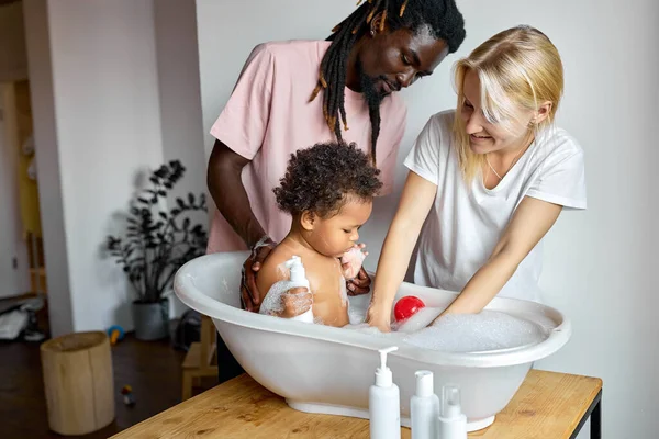 Vicces fekete baba fürdés kis fürdőkádban. gyermekkor, szülőség fogalma. — Stock Fotó