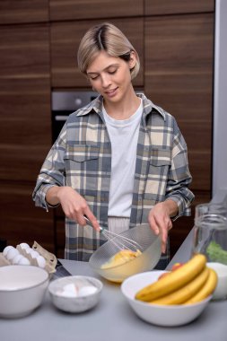 Mutlu kadın evde kurabiye pişirmek için muz ve hamuru eziyor.