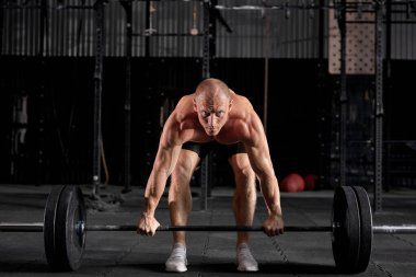 Modern karanlık spor salonunda halterle egzersiz yapan kendine güvenen sağlıklı bir sporcu..