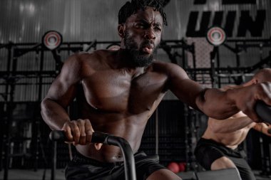 Genç Afro-Amerikan aktif, kaslı, terli ve kaslı bir adam kardiyo çalışması yapıyor.