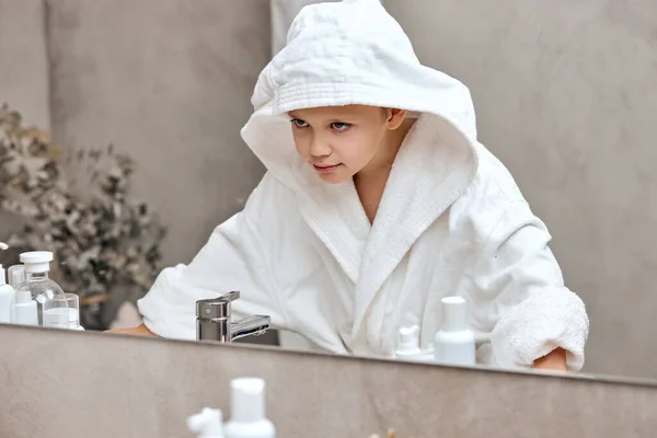 아침에 거울 앞에 서서 목욕 가운을 입고 있는 웃긴 남학생 — 스톡 사진