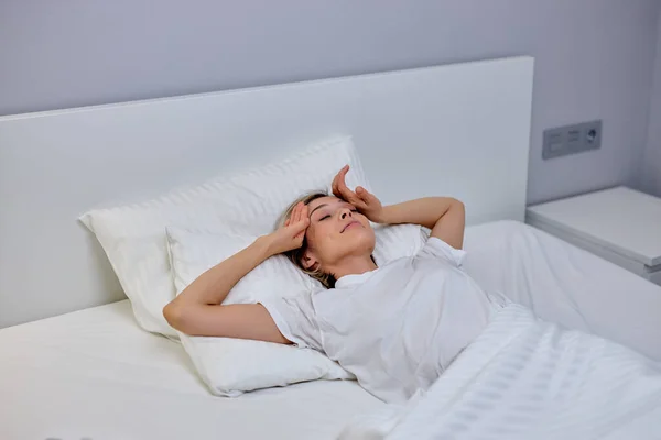 Wanita yang santai terbaring di tempat tidur setelah tidur, bangun lebih awal, tidak cukup tidur — Stok Foto