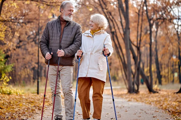 Ajuste amigável casal maduro de cabelos grisalhos em casacos desfrutando de atividade física promotora de saúde — Fotografia de Stock