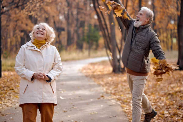 Temporada de Outono. Família casal envelhecido jogando folhas na floresta de outono, se divertindo ao ar livre — Fotografia de Stock