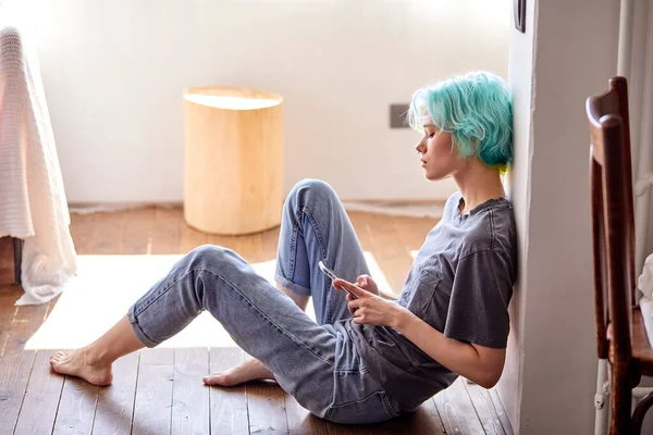 Ung kvinna sitta med smartphone på golvet tänker vad man ska skriva, skriva meddelande — Stockfoto