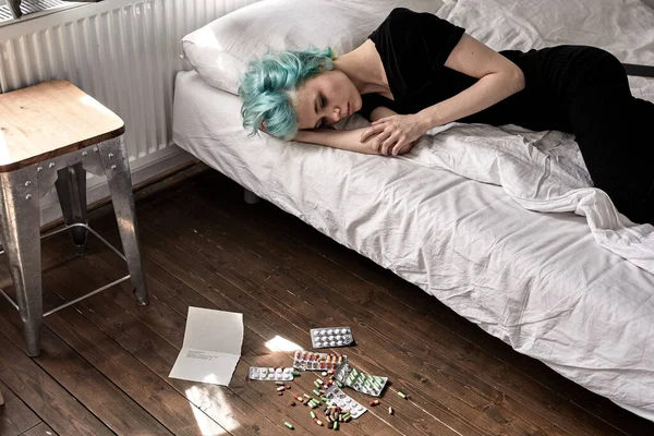 Tabletten auf dem Boden verteilt, Frau liegt nach Tablettenüberdosis zu Hause im Bett — Stockfoto