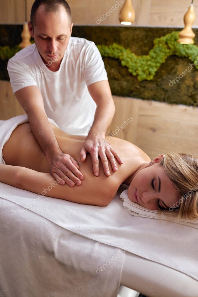 Masajista profesional masajea la espalda de una joven rubia - Main Image