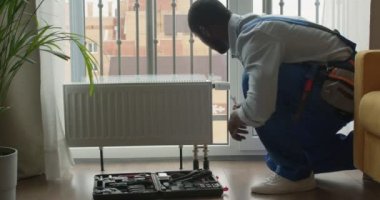 Adam odadaki radyatör aküsünü tamir ediyor. Tamir işleri dairede yenileniyor.