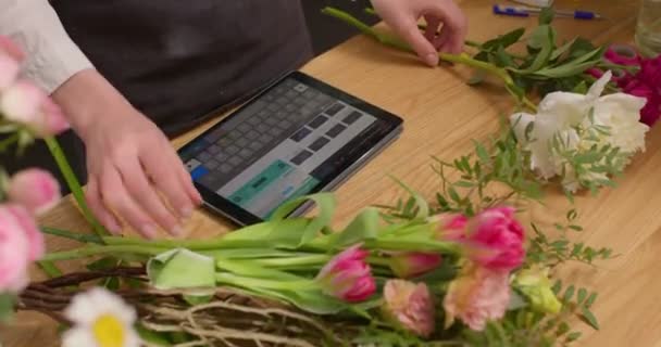 Blumenhändlerin mit Tablet-PC am Blumenladen-Tresen. junge nette Floristin mit digitalem Tablet — Stockvideo