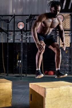 Aktif, güçlü, uyumlu, terli, iri kaslı, atlama egzersizi yapan bir afro adam.