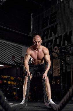 Spor. Savaş halatları seansı. Gömleksiz, beyaz, formalı sporcu.