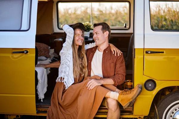 Joyful young couple sitting inside of campervan while looking outside of the van — Stock Photo, Image