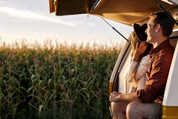 Vista lateral de la encantadora pareja sentada en una camioneta desde atrás mirando el atardecer, en contemplación —  Fotos de Stock