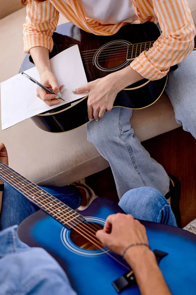 Vue du dessus sur jeune couple composant une chanson, tenant une guitare acoustique, écrivant sur papier — Photo