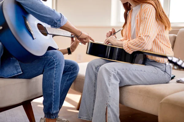 Couple recadré en amour assis sur le canapé tandis que jeune homme enseignant petite amie jouer de la guitare — Photo