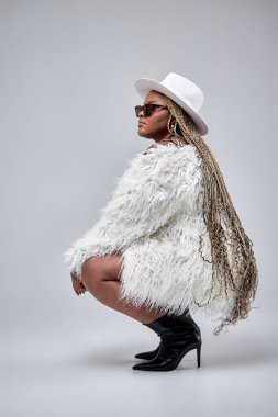 Gri stüdyo arka planında poz veren şık elbiseli tombul bir kadın. Büyük boy model