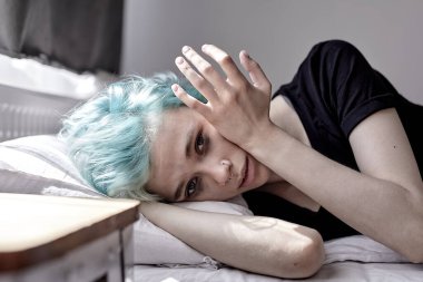 Genç bir kadın yatakta acı içinde yatıyor, regl sancıları çekiyor. Bunalımlı yalnız kadın