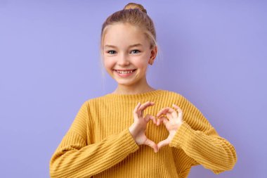 Tatmin olmuş genç bir kızın kalp işareti, aşk konsepti gösteren yakın plan portresi.