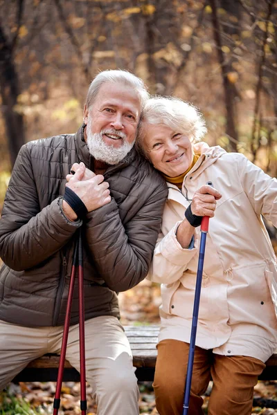 Feliz casal de idosos apaixonados envolvidos em caminhada nórdica no parque, descansar — Fotografia de Stock