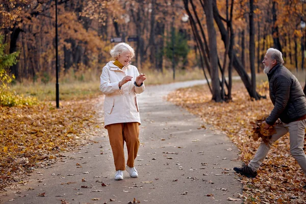 Homem alegre e mulher 60-70 anos de idade se divertir rindo, durante a caminhada na floresta de outono — Fotografia de Stock