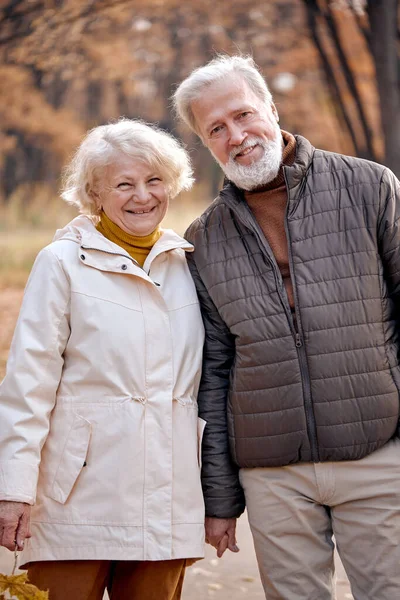 Alegre casal sênior caucasiano posando na câmera enquanto caminhava na floresta — Fotografia de Stock