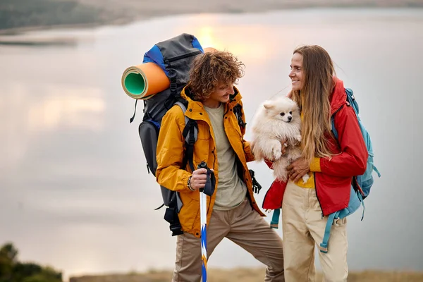 Belo casal brincar com spitz cão desfrutar da paisagem do lago no fundo, viajar — Fotografia de Stock