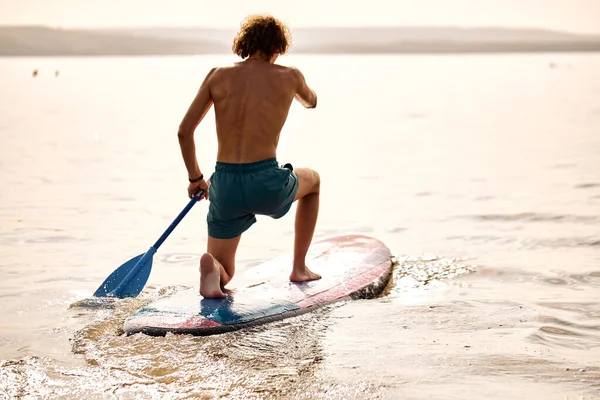 Erfahrener männlicher Surfer, der auf einem Surfbrett steht und sich auf hohe Wellen vorbereitet. — Stockfoto