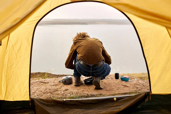 Vista posteriore sul maschio preparare falò, vista dalla tenda, vista da dietro — Foto Stock