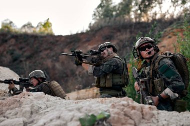 team of confident Army soldiers in protective combat uniform posing, looking at side holding special operations forces combat assault rifle, in protective combat uniform, soldiers engaged.