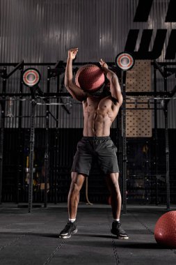Afrikalı sporcu spor salonunda sıkı antrenman yapıyor, omuzlar, göğüs, pazılar, kol ve kollar için top egzersizleri yapıyor, vücut üzerinde çalışıyor. Fitness, sağlıklı ve kendini kontrol etme konsepti. kros uygun eğitim