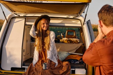 Side view on young caucasian pretty woman posing at camera while husband is taking photo of her, attractive long-haired lady enjoy spending time in countryside, travelling. people lifestyle concept