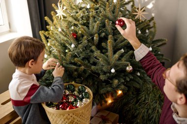 Father and son decorating Christmas tree. Funny family at home in living room. Son and dad enjoy celebrating 2021 new year. happy family, have fun, looking forward xmas. celebration, new year concept