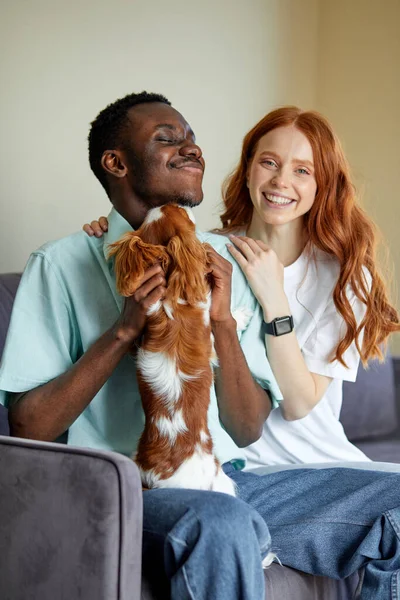 Joyful Black Man Caucasian Woman Sit Sofa Embarrassing Playing Pet — Foto de Stock